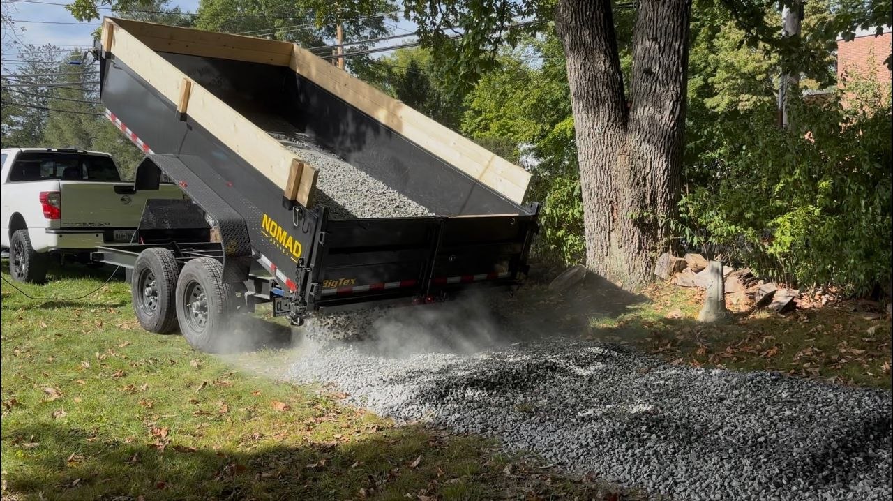 Dump trailer delivering stone onto a property